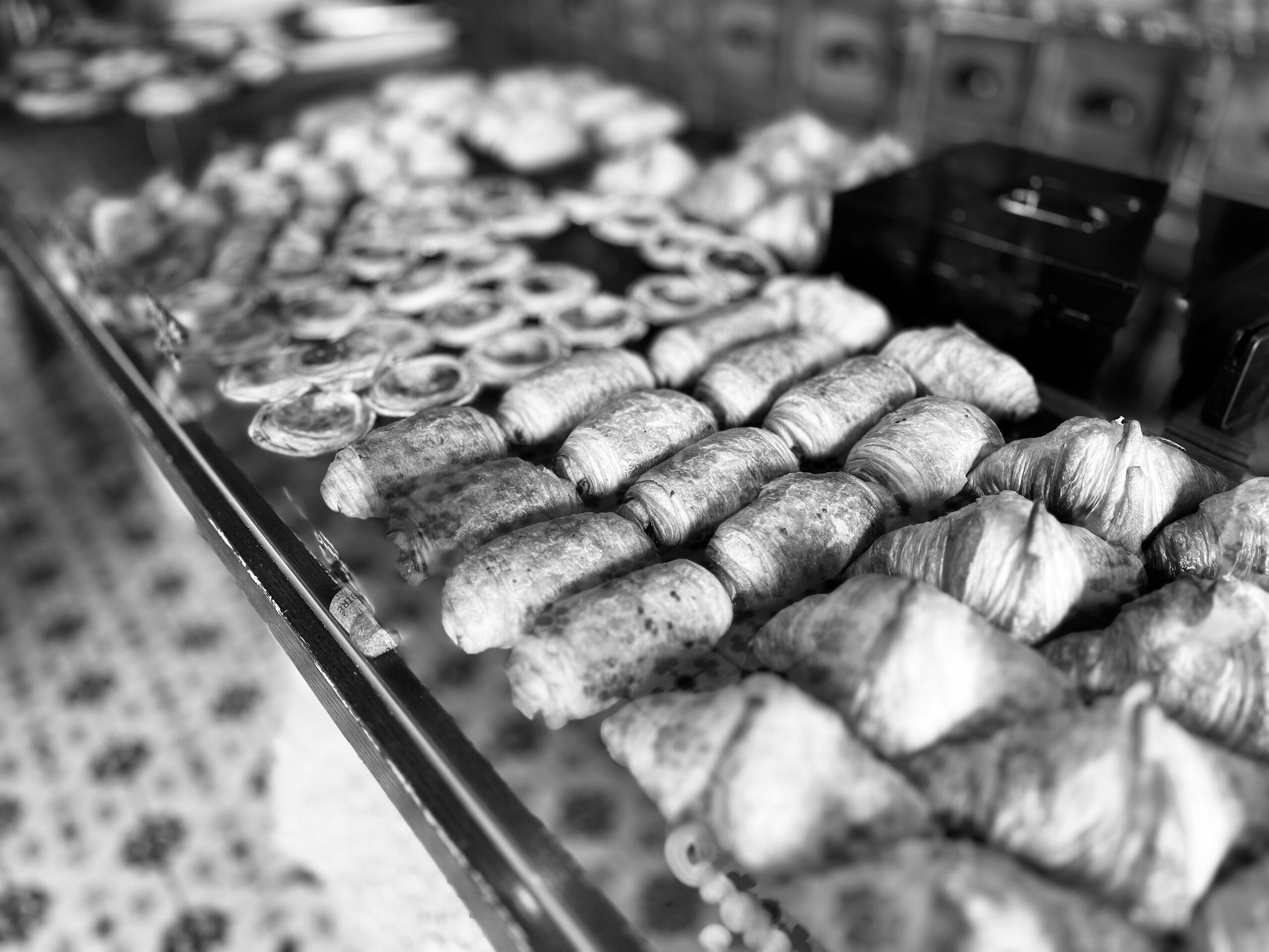 A bakery counter: rows of croissants, strudel and filled pastries behind glass.