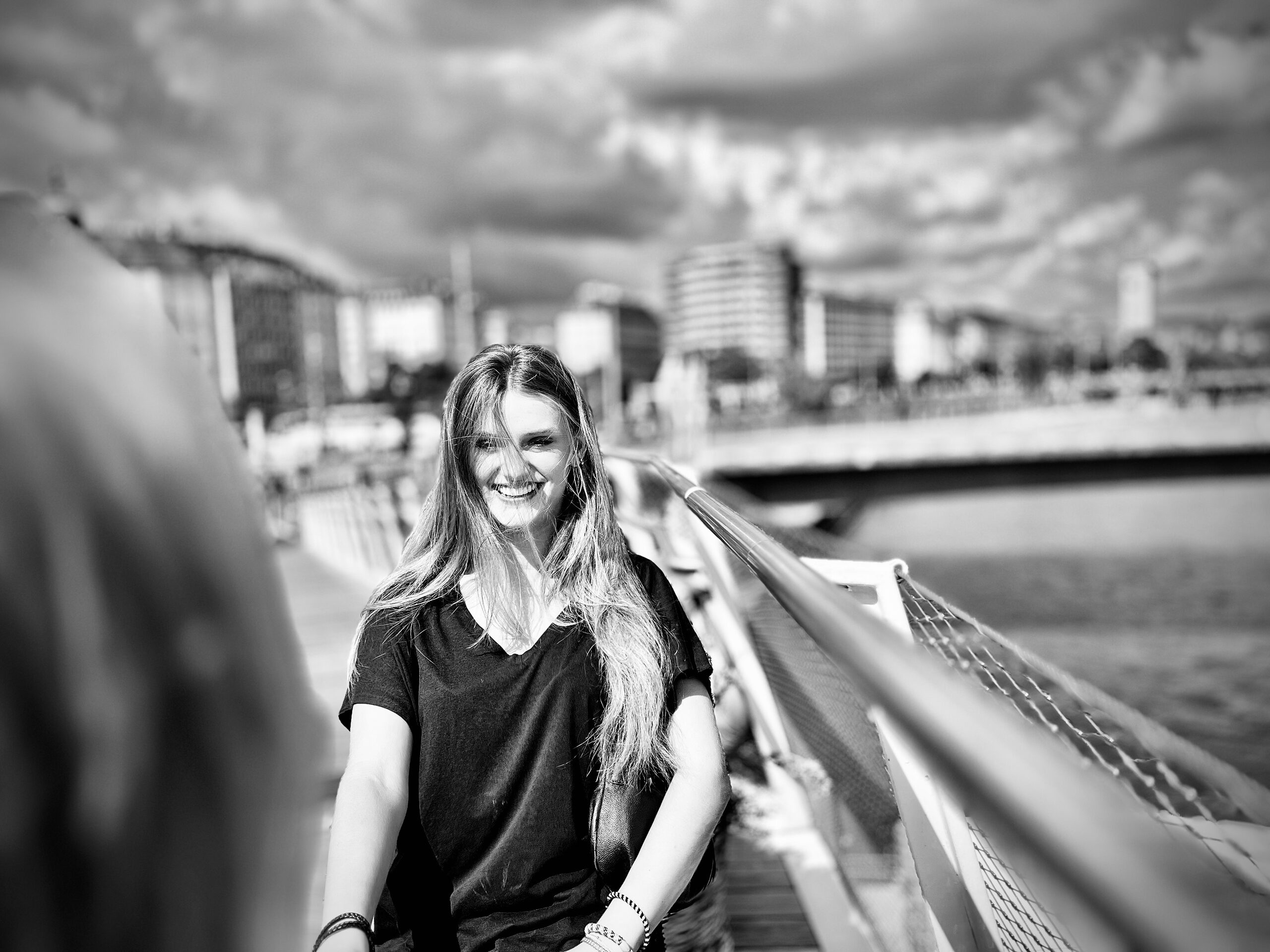 A woman at the bridge railing, the Danube canal and the buildings along it behind her.