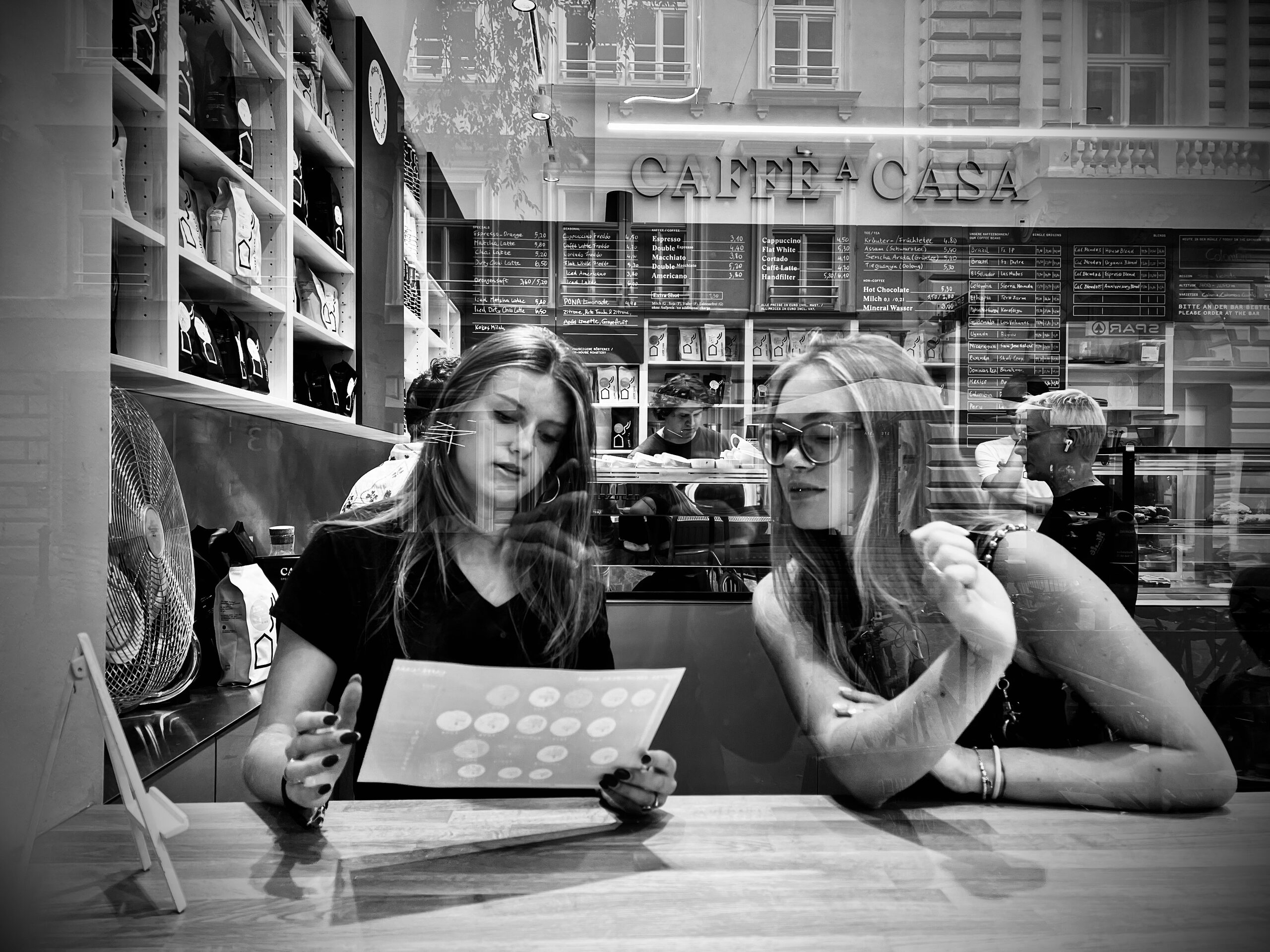 Two women at a café table, the open menu between them.